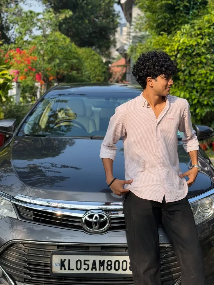 Candid Young Man in Pink Striped Shirt Leaning on Toyota Car in Driveway