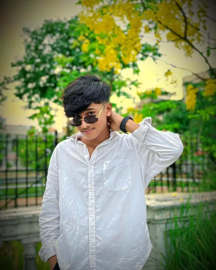 Candid Outdoor Waist-Up Portrait of Stylish Young Indian Man Under Yellow Blossom Tree