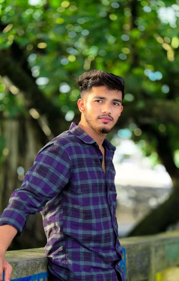 Candid Outdoor Waist-Up Portrait of Young Indian Man Leaning by Low Wall Under Trees