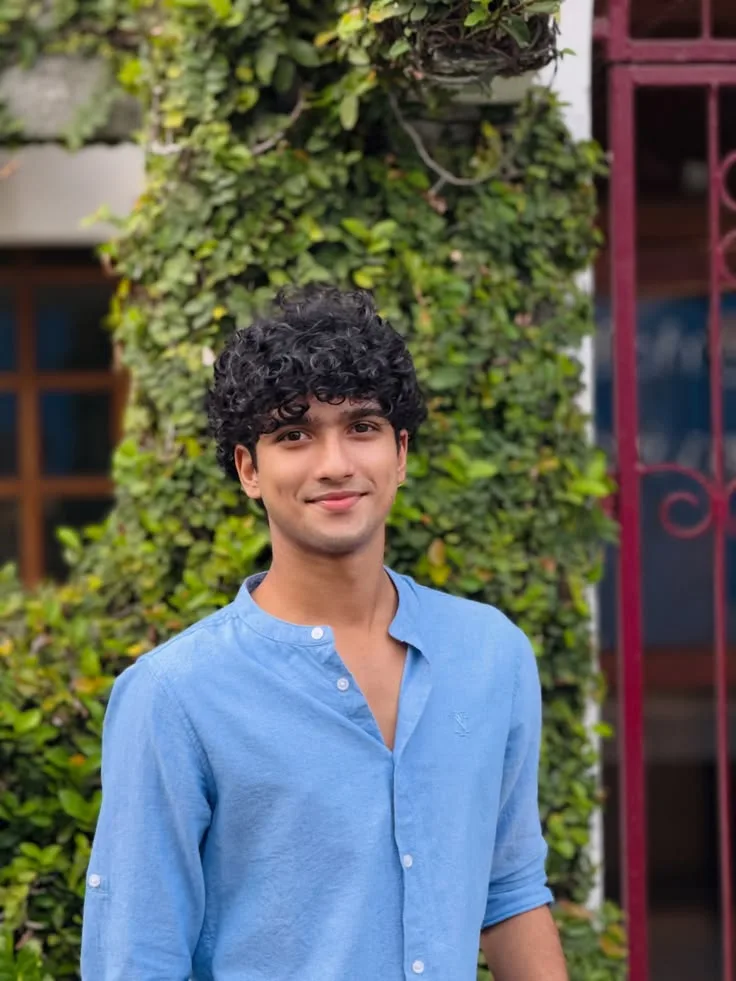 Candid Outdoor Portrait of Young Man with Curly Hair in Cornflower Blue Linen Shirt