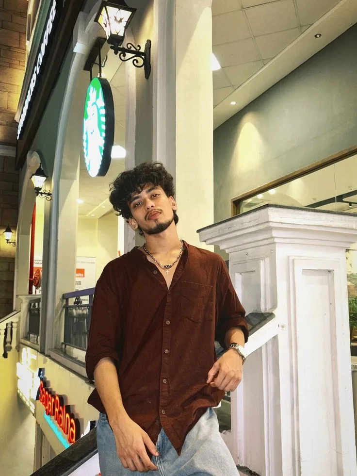 Candid Young Man Posing near Mall Railing with Coffee Shop Sign