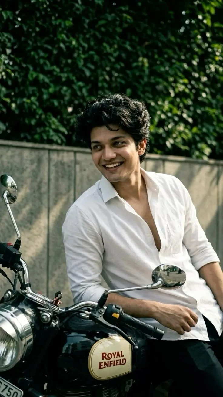 Candid Young Man in White Button-Down Shirt Smiling Beside Vintage Royal Enfield Motorcycle