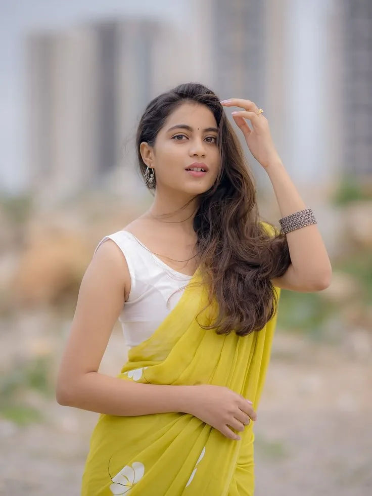 Candid Young Woman in Bright Yellow Saree Touching Hair Outdoors