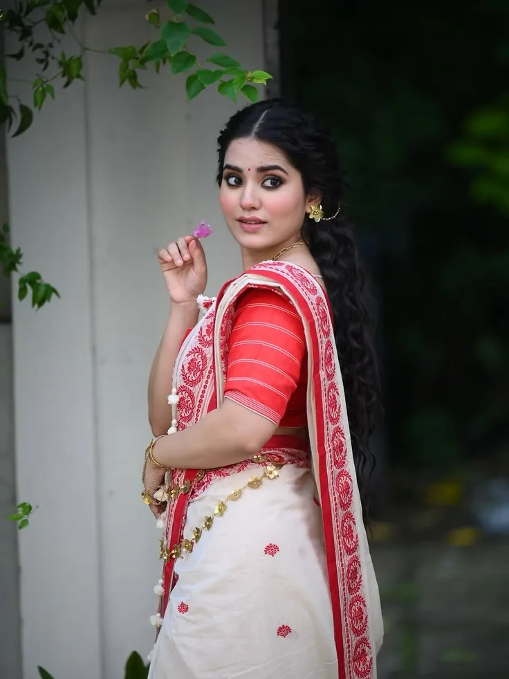 Candid Bengali Festive Portrait of Young Woman in Lal Paar Saree Holding Bougainvillea Flower