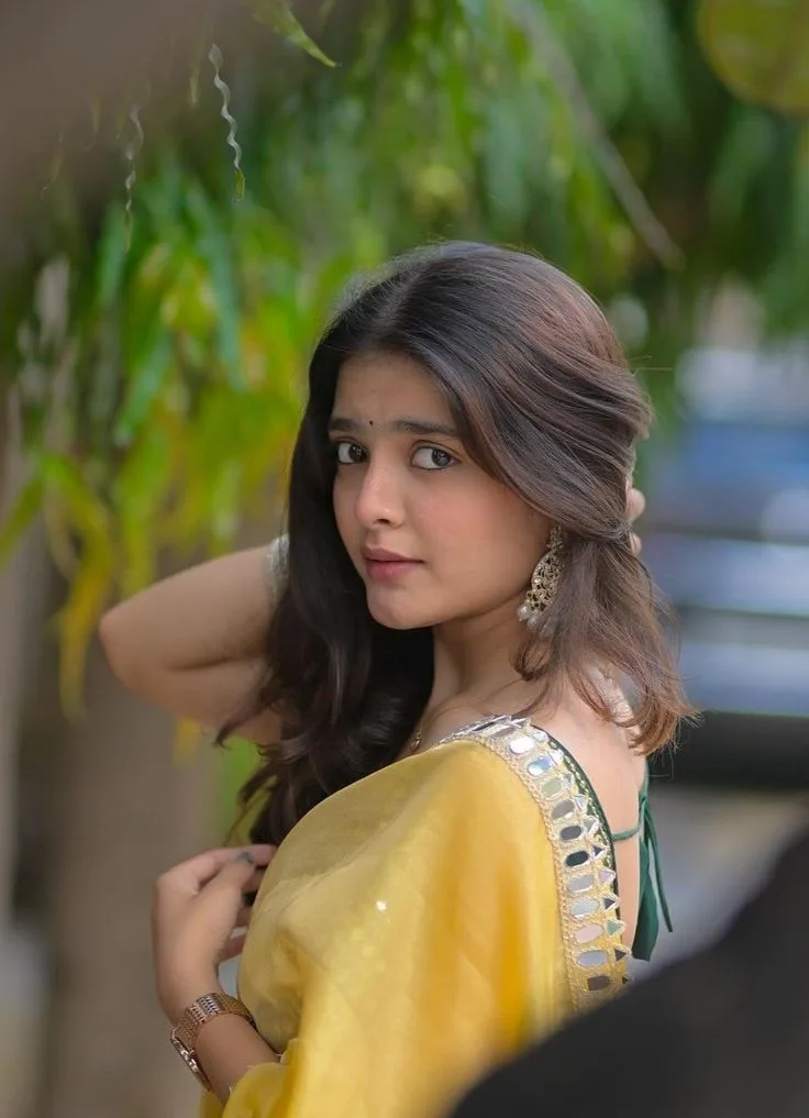 Candid Young Woman in Yellow Mirror-Work Saree Glancing Over Shoulder Outdoors