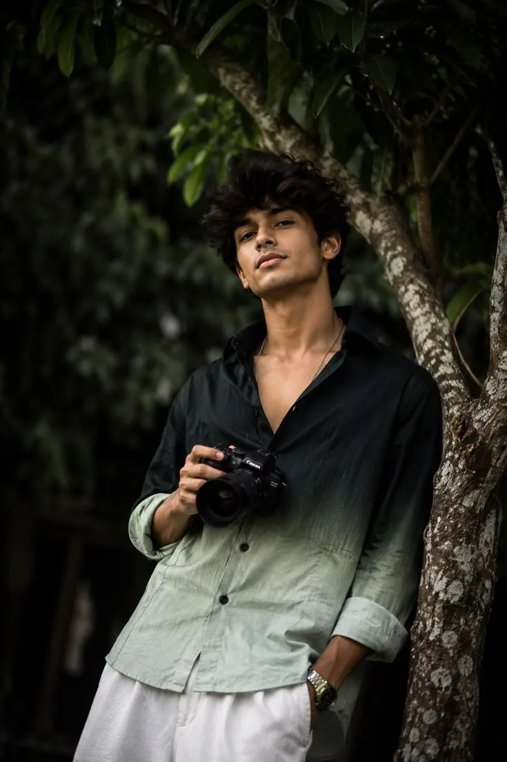 Candid Outdoor Waist-Up Portrait of Young Indian Photographer Leaning on Tree