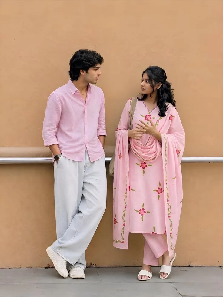 Candid Couple in Coordinated Pastel Pink Outfits Leaning Against Ochre Wall