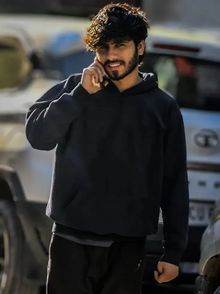 Candid Street Style Portrait of Young Man with Textured Curly Fringe on Phone in Black Hoodie