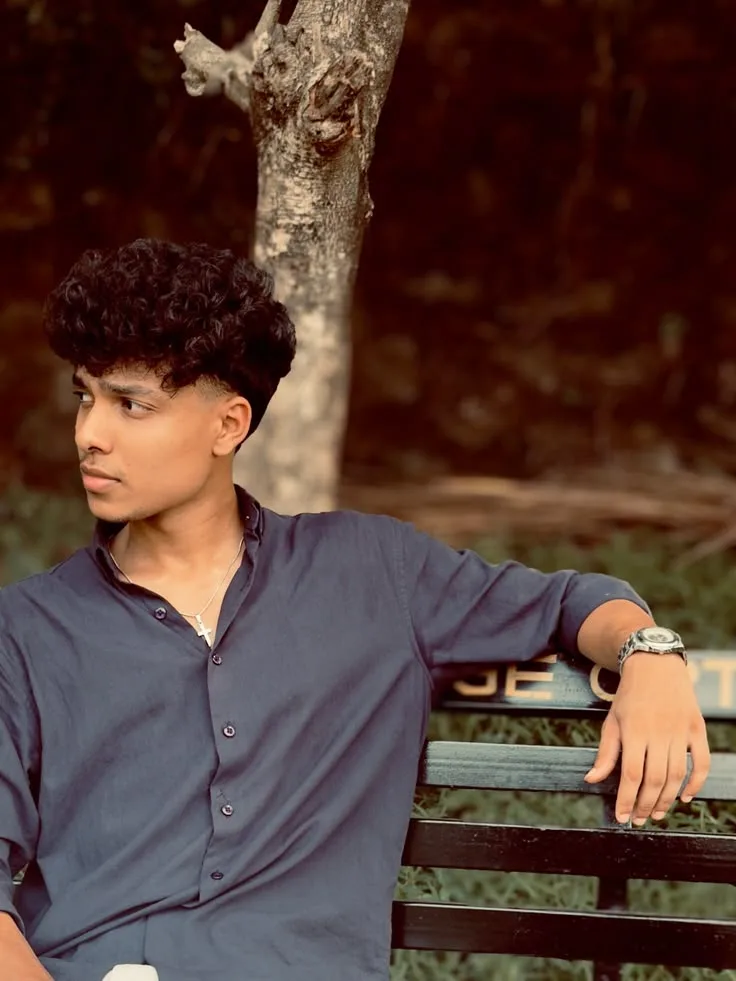 Candid Young Man in Navy Shirt Seated on Park Bench Looking to the Side