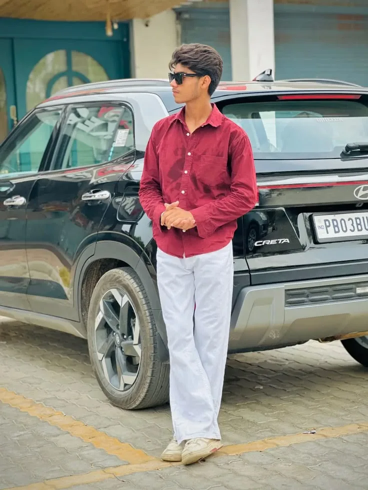 Candid Young Man in Maroon Shirt with Clasped Hands by Black SUV