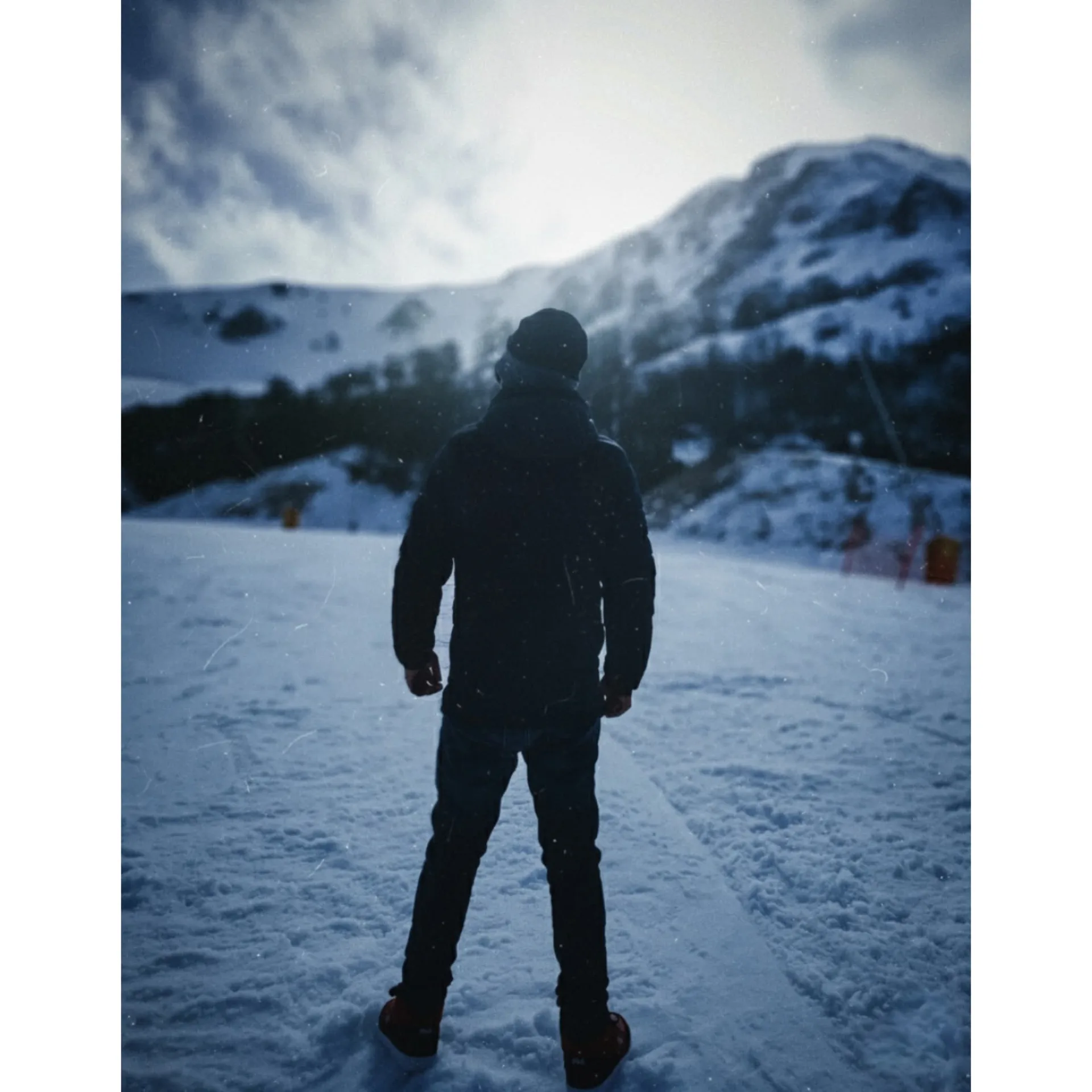 Cinematic rear view of a lone person standing on a snowy