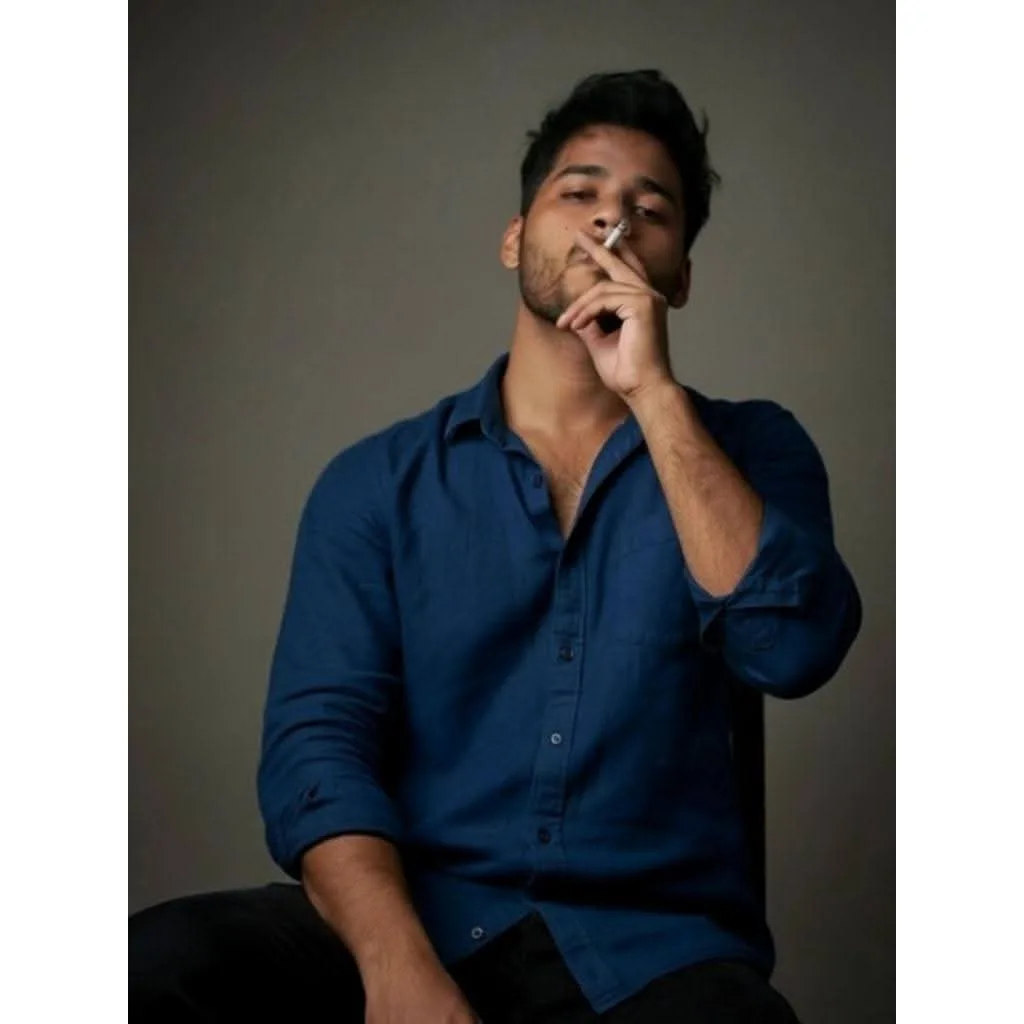 A young South Asian man with dark wavy hair and light